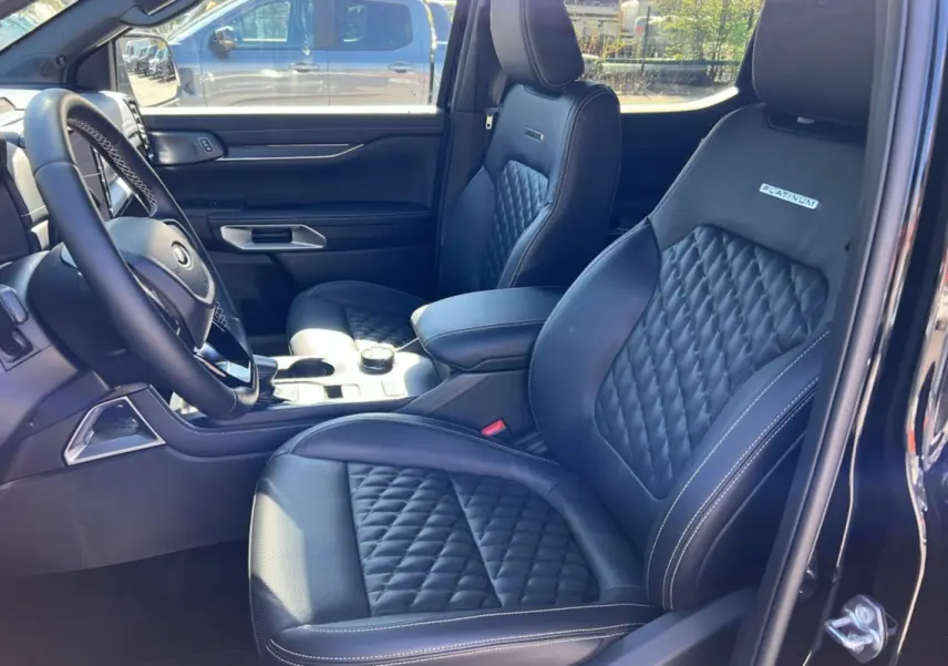 Vue intérieure côté conducteur du Ford Ranger 2026 noir agate, sièges cuir matelassés avec logo Platinum visible.