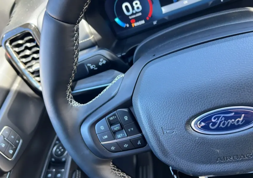 Gros plan sur le volant cuir noir du Ford Ranger 2026 avec commandes multifonctions et tableau de bord numérique.
