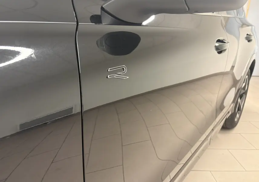 Vue latérale droite rapprochée du Volkswagen Tiguan 2025 noir intense nacré avec logo R sur la porte avant.