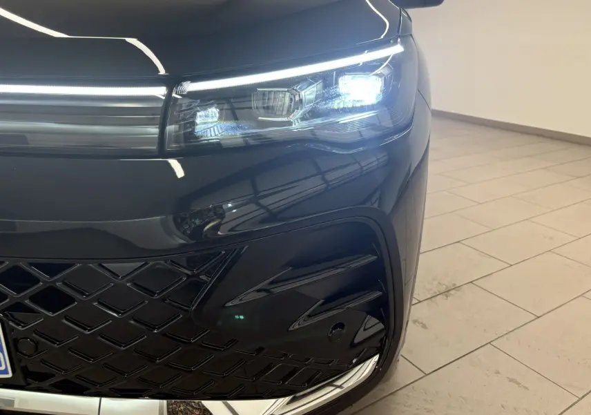 Gros plan sur l'avant droit du Volkswagen Tiguan 2025 noir intense nacré, mettant en valeur le phare LED et la calandre R-Line.