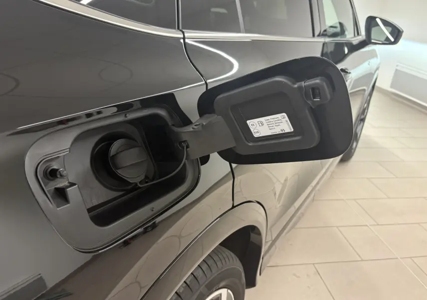 Vue côté gauche arrière du Volkswagen Tiguan noir intense nacré avec trappe de carburant essence ouverte.
