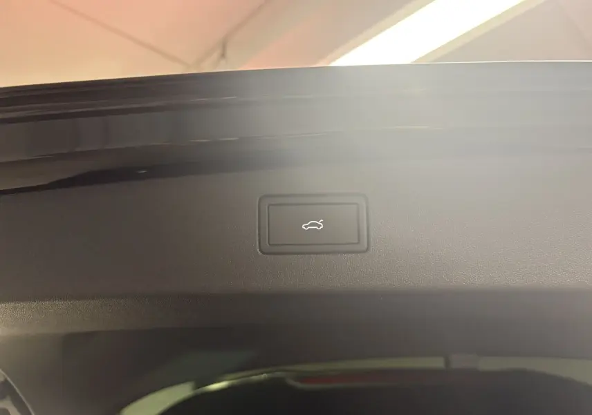 Bouton d'ouverture électrique du coffre sur le hayon intérieur d'un Volkswagen Tiguan noir intense nacré.