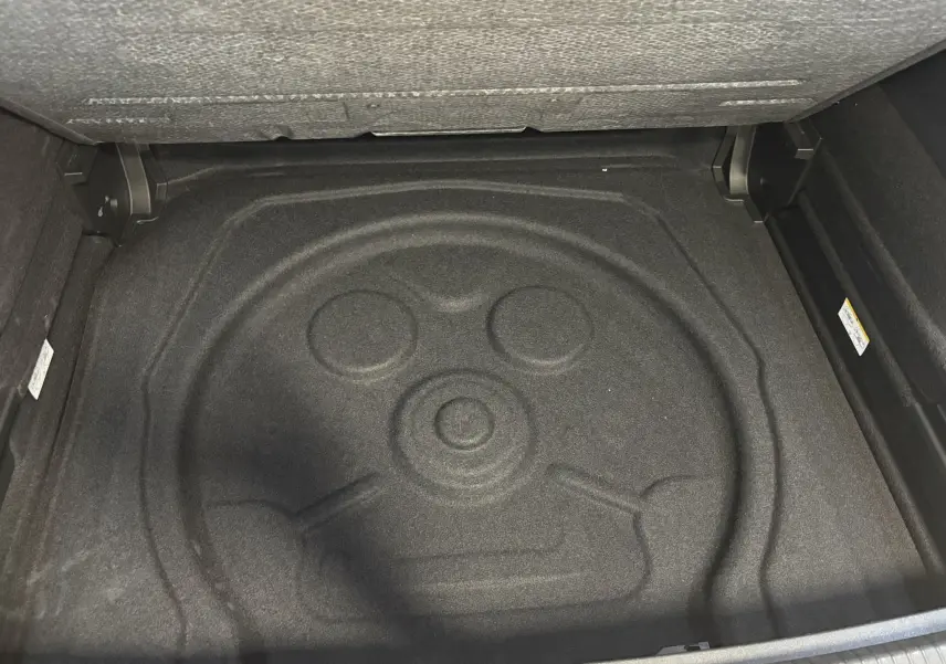 Coffre ouvert du Volkswagen Tiguan 2025, vue plongeante sur l’espace de rangement avec tapis de sol noir.