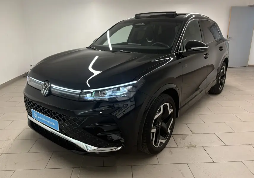 Vue 3/4 avant droite du Volkswagen Tiguan 2025 noir intense nacré avec jantes R-Line et toit ouvrant visible.