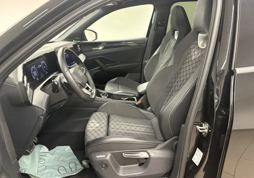 Vue intérieure côté conducteur du Volkswagen Tiguan 2025 noir nacré, sièges sport R-Line avec surpiqûres bleues et tableau de bord digital.