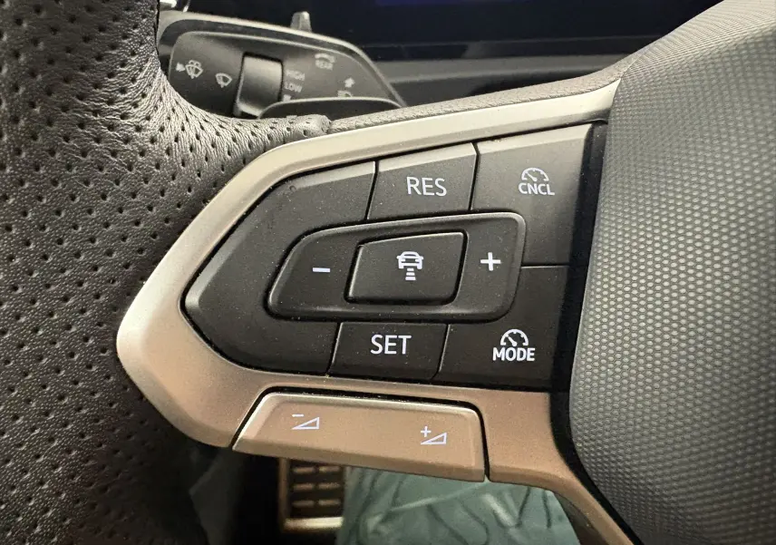 Gros plan sur les commandes au volant du Volkswagen Tiguan 2025, boutons noirs avec finitions argentées.