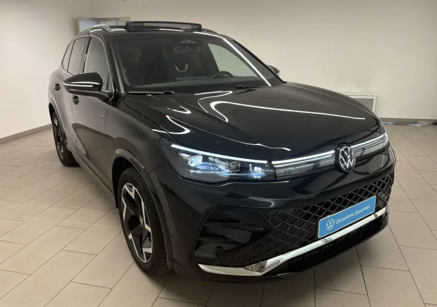 Vue 3/4 avant gauche du Volkswagen Tiguan 2025 noir intense nacré avec calandre R-Line et jantes alliage distinctives.