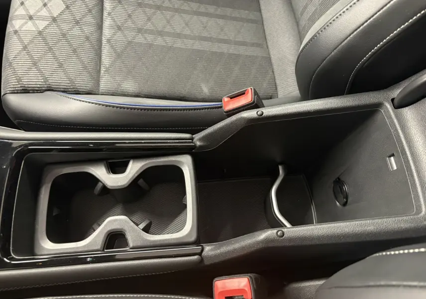 Vue rapprochée de la console centrale noire avec porte-gobelets et accoudoir ouvert du Volkswagen Tiguan 2025.