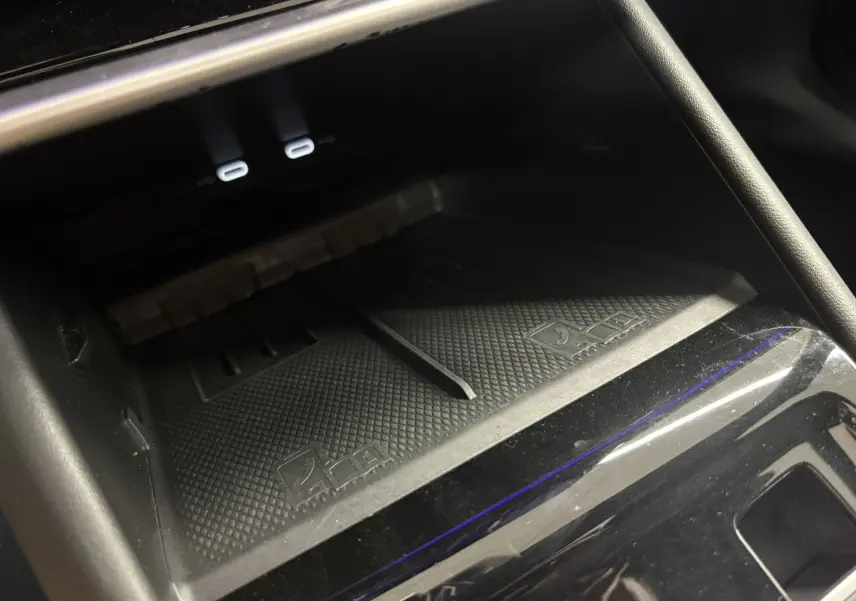 Détail de la console centrale du Volkswagen Tiguan 2025, zone de recharge sans fil avec deux ports USB-C éclairés.