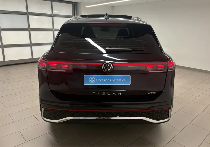 Vue arrière du Volkswagen Tiguan 2025 noir intense nacré avec feux LED étirés et logo central lumineux.