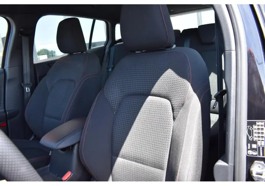 Vue intérieure rapprochée des sièges avant noirs avec surpiqûres rouges d’une Ford Focus SW 2025 Agate Black Metallic.