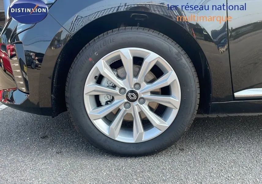 Gros plan sur la roue avant gauche de la Renault Clio noire étoile métal, mettant en valeur la jante alliage et le logo Renault central.