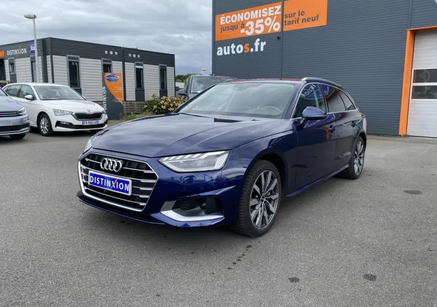 Audi A4 Avant bleu Navarre vue 3/4 avant droit avec jantes 5 branches et calandre chromée sur parking extérieur