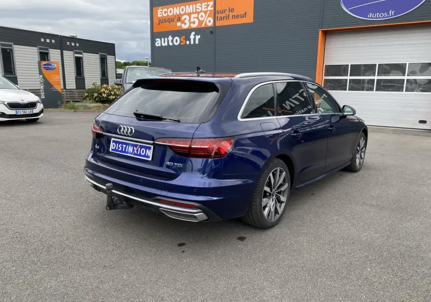 Audi A4 Avant bleu Navarre en 3/4 arrière droit, avec crochet d'attelage et jantes 18 pouces gris contrasté.