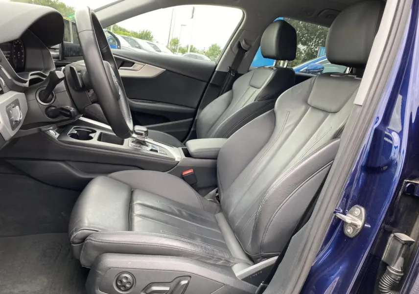 Vue intérieure côté conducteur d'une Audi A4 Avant 2022 bleu Navarre avec sièges sport en cuir noir et console centrale visible.