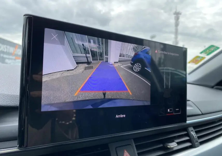 Écran central montrant la caméra de recul de l'Audi A4 Avant bleu Navarre, avec guidage de trajectoire en parking.