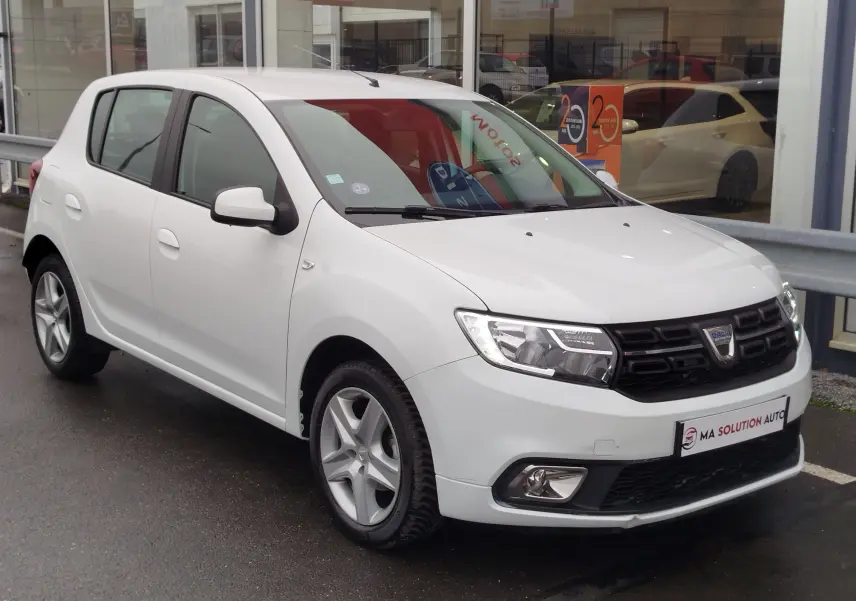 Dacia Sandero blanc glacier vue 3/4 avant droit, avec calandre noire et jantes alliage cinq branches.