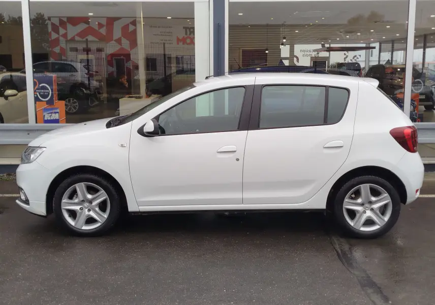 Profil côté gauche d'une Dacia Sandero blanc glacier de 2019, version Lauréate Easy-R, garée devant une vitrine.