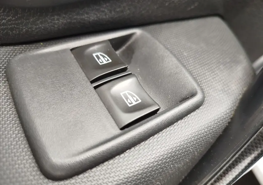Gros plan sur les boutons de commande des vitres électriques noirs dans l'habitacle d'une Dacia Sandero blanc glacier 2019.