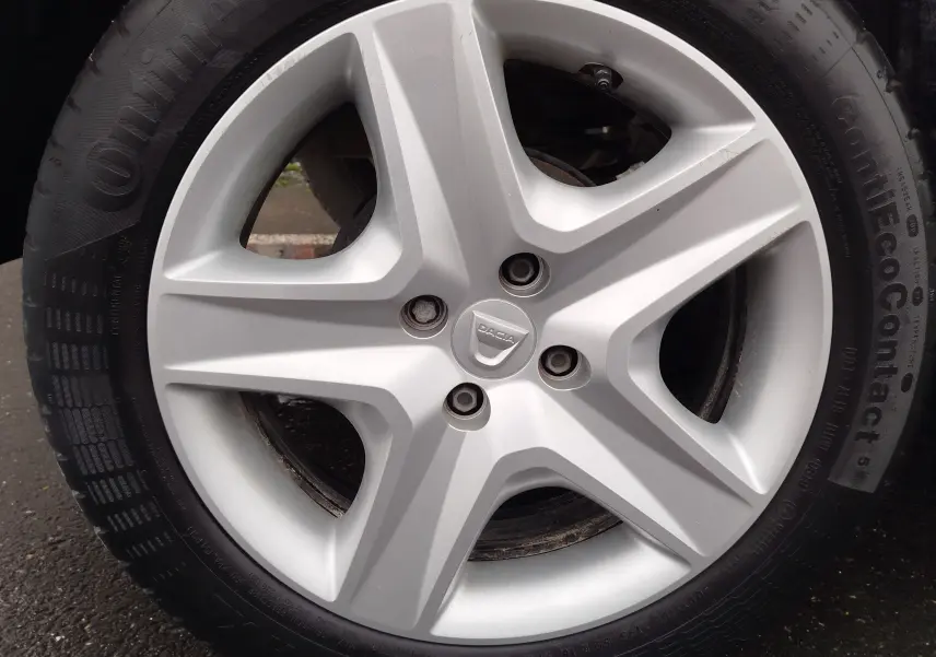 Vue de profil côté gauche d'une Dacia Sandero blanc glacier de 2019 avec jantes visibles sur sol asphalté.