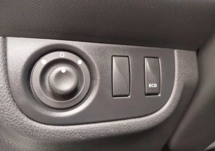 Gros plan sur les commandes de réglage des rétroviseurs et bouton ECO à l'intérieur d'une Dacia Sandero blanc glacier 2019
