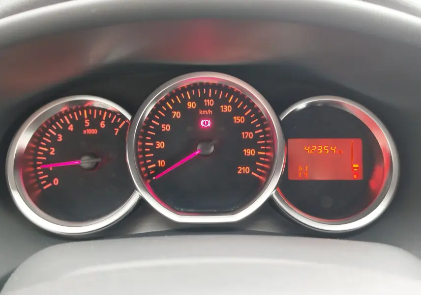 Tableau de bord éclairé avec compte-tours, compteur de vitesse et écran digital d'une Dacia Sandero blanc glacier 2019.