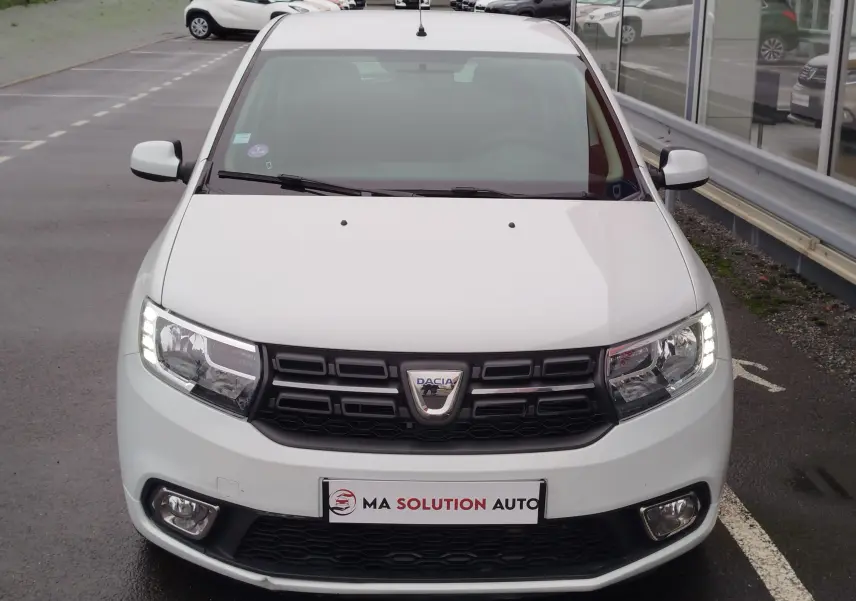 Vue avant d'une Dacia Sandero blanc glacier de 2019 avec phares LED allumés et calandre noire distinctive.