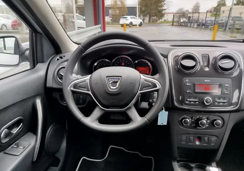Intérieur de la Dacia Sandero 2019 vue depuis le siège conducteur, tableau de bord noir avec volant et console centrale.