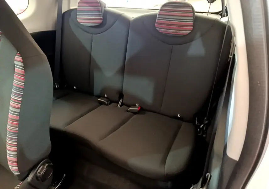Vue intérieure de la banquette arrière noire avec appuie-têtes rayés rouges et gris de la Citroën C1 blanche.