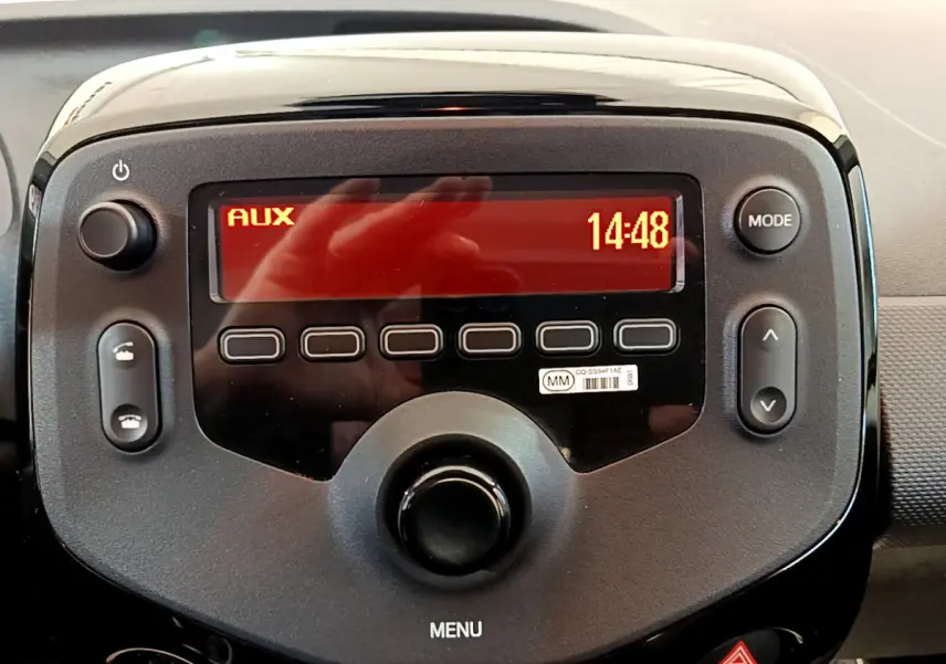 Gros plan sur la console centrale noire de la Citroën C1 2020 avec écran rouge affichant "AUX" et l'heure 14:48.