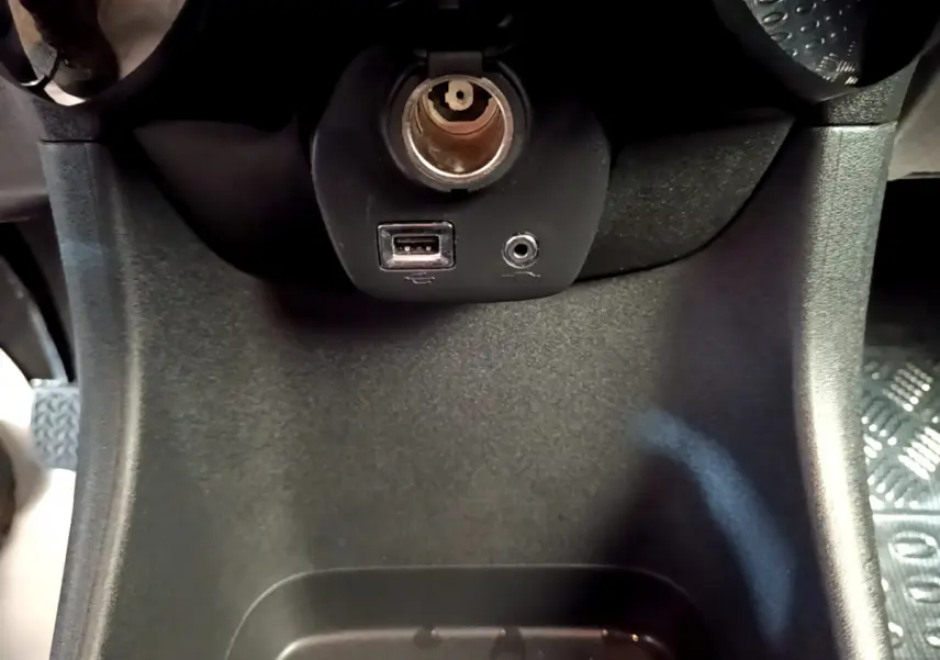 Prise USB et prise jack sur la console centrale noire de la Citroën C1 blanche, vue en gros plan intérieur.