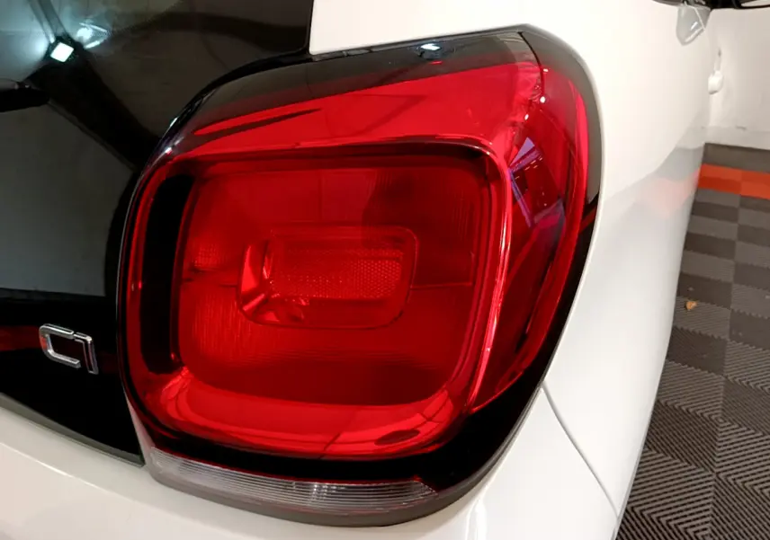 Gros plan sur le feu arrière droit rouge d'une Citroën C1 blanche, version 2020, avec partie arrière noire brillante.