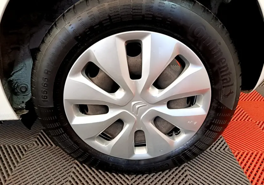 Gros plan sur la roue avant droite blanche d'une Citroën C1 2020 avec enjoliveur argenté et pneu Continental.