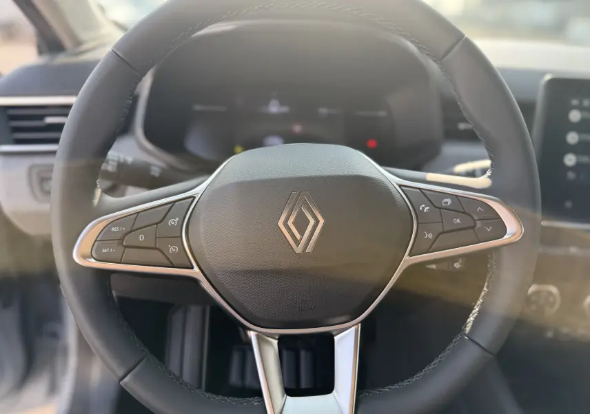 Vue rapprochée du volant noir de la Renault Clio 1.5 DCI 100CH Evolution avec commandes intégrées, intérieur lumineux.
