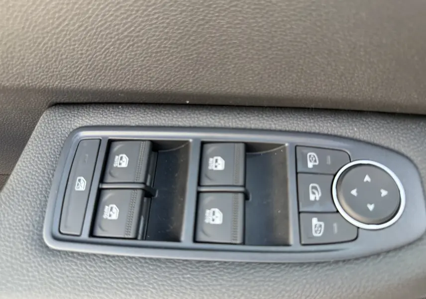 Panneau de commandes des vitres et rétroviseurs côté conducteur dans l'habitacle d'une Renault Clio gris Rafale métal.