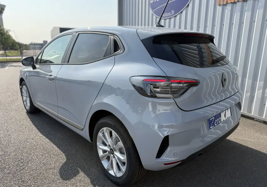 Vue 3/4 arrière droite d'une Renault Clio gris Rafale métal 2025 avec feux arrière LED et plaque Zero KM.