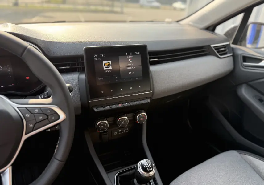 Intérieur avant droit de la Renault Clio gris Rafale Métal 2025, avec tableau de bord moderne et boîte manuelle visible.