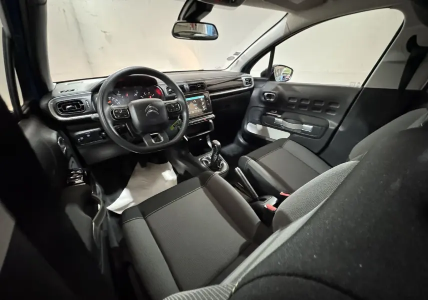 Vue intérieure avant droite de la Citroën C3 2018, tableau de bord noir avec écran tactile et sièges tissu gris.