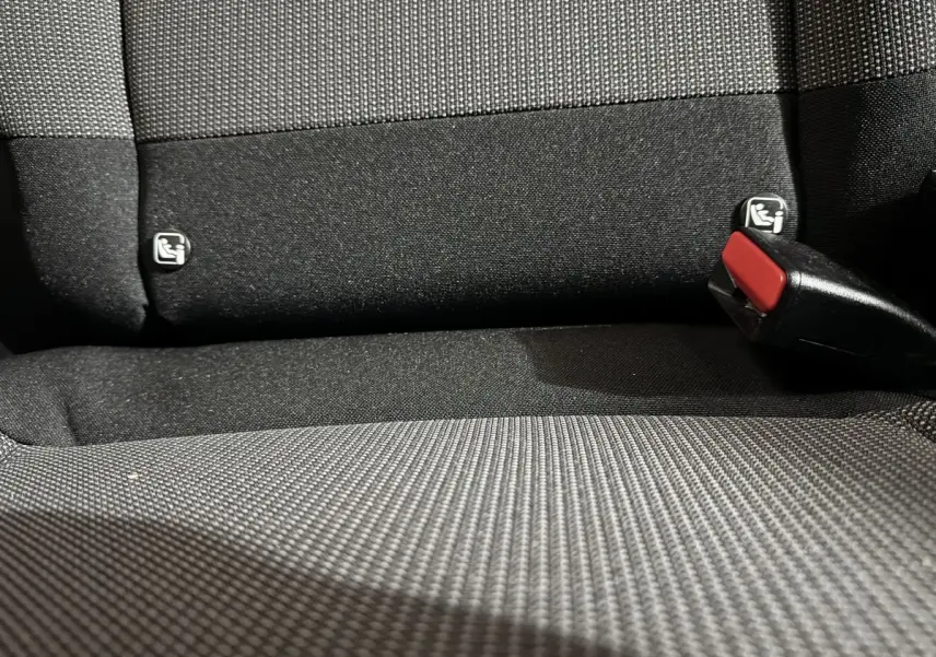 Gros plan sur la banquette arrière noire de la Citroën C3 avec fixation Isofix et boucle de ceinture rouge visible.