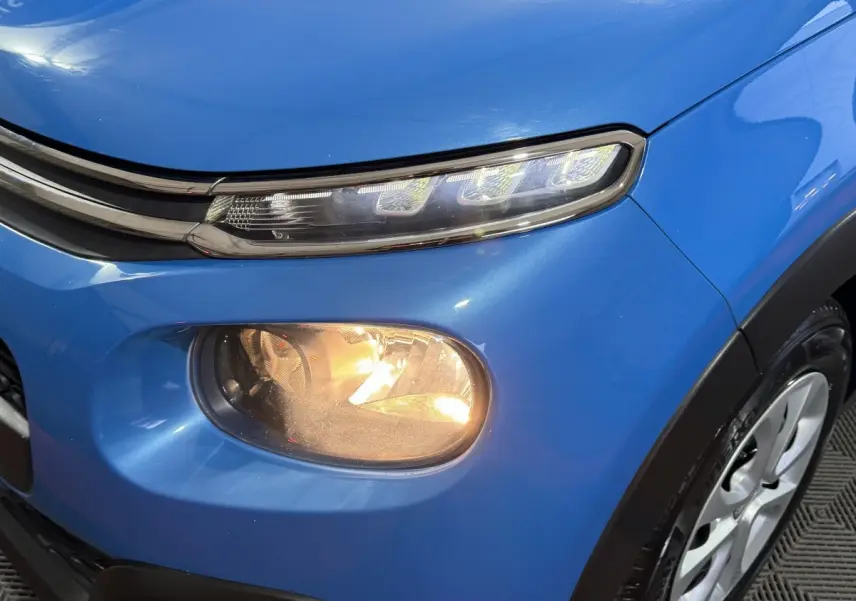 Gros plan sur l'avant droit bleu d'une Citroën C3 2018 avec phares LED et antibrouillard allumé.