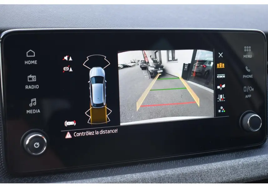 Écran tactile intérieur affichant la caméra de recul et les capteurs de distance du Skoda Scala blanc glacier.