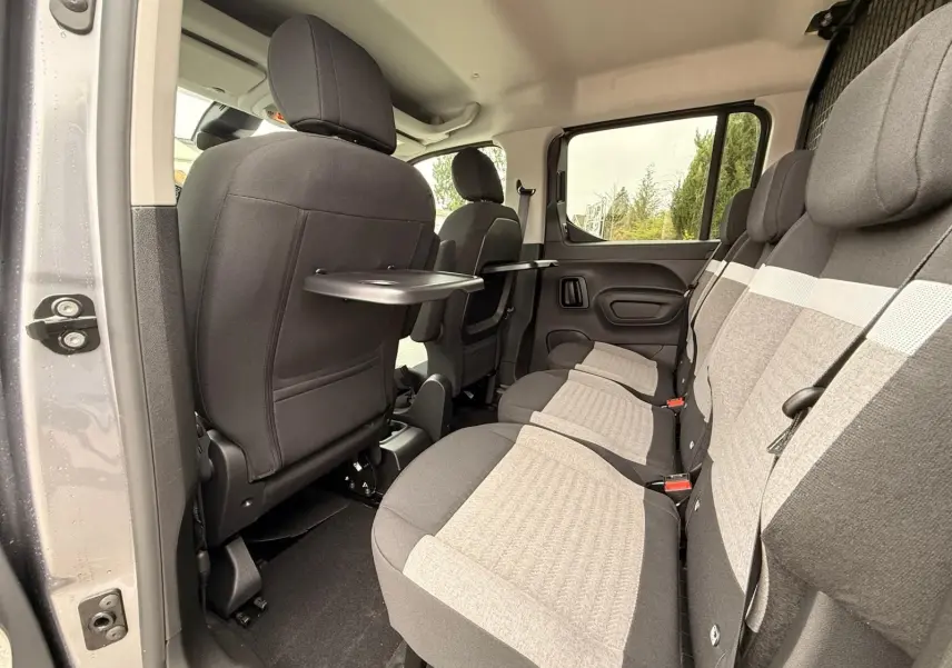 Vue intérieure côté droit du Citroën Berlingo gris Artense 2025, montrant la banquette arrière et les tablettes rabattables.