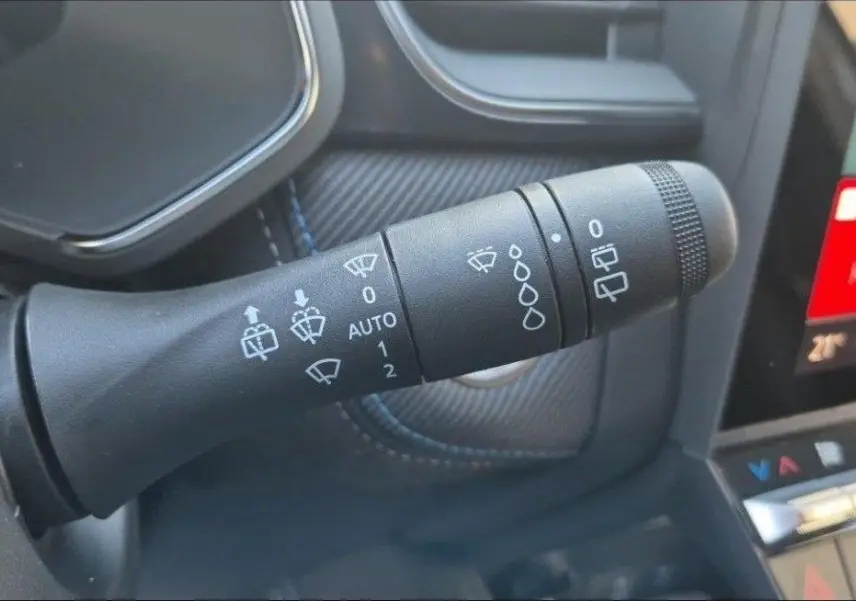 Gros plan sur la commande des essuie-glaces du Renault Captur E-Tech hybride 2025, intérieur noir avec surpiqûres bleues.