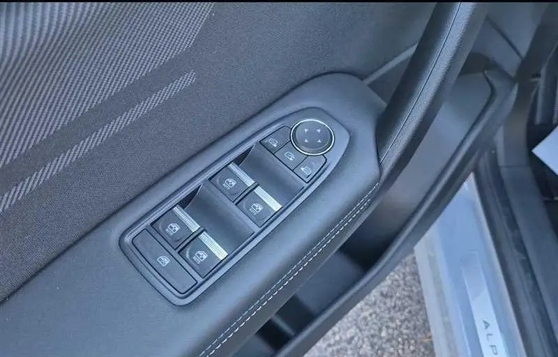 Gros plan sur les commandes des vitres et rétroviseurs sur la porte côté conducteur du Renault Captur gris Rafale 2025.
