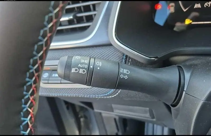 Gros plan sur la commande des feux et clignotants du Renault Captur E-Tech gris, avec volant à surpiqûres tricolores visible.