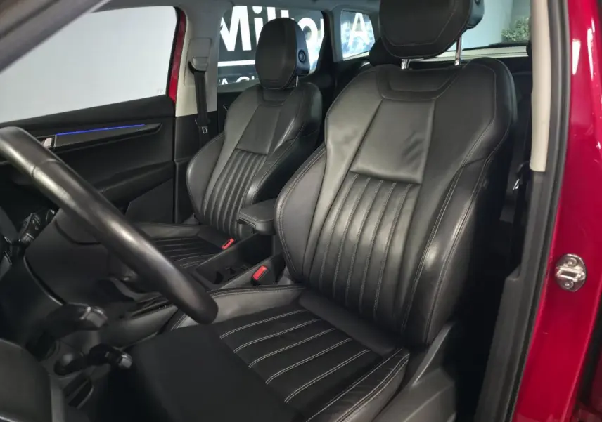 Intérieur du SKODA KAROQ rouge, vue côté gauche sur sièges avant en cuir noir avec surpiqûres blanches.