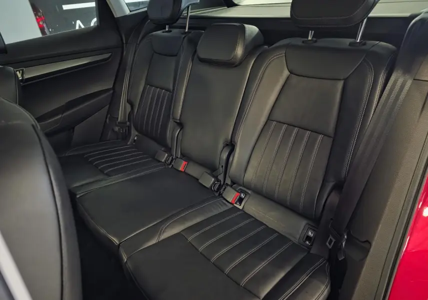 Vue intérieure des sièges arrière en cuir noir du Skoda Karoq rouge, avec ceintures de sécurité et appuie-têtes visibles.