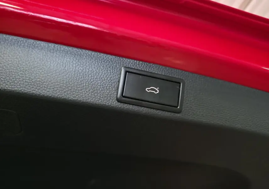 Bouton d'ouverture du hayon noir sur intérieur de coffre rouge d'un Skoda Karoq Style 2018.