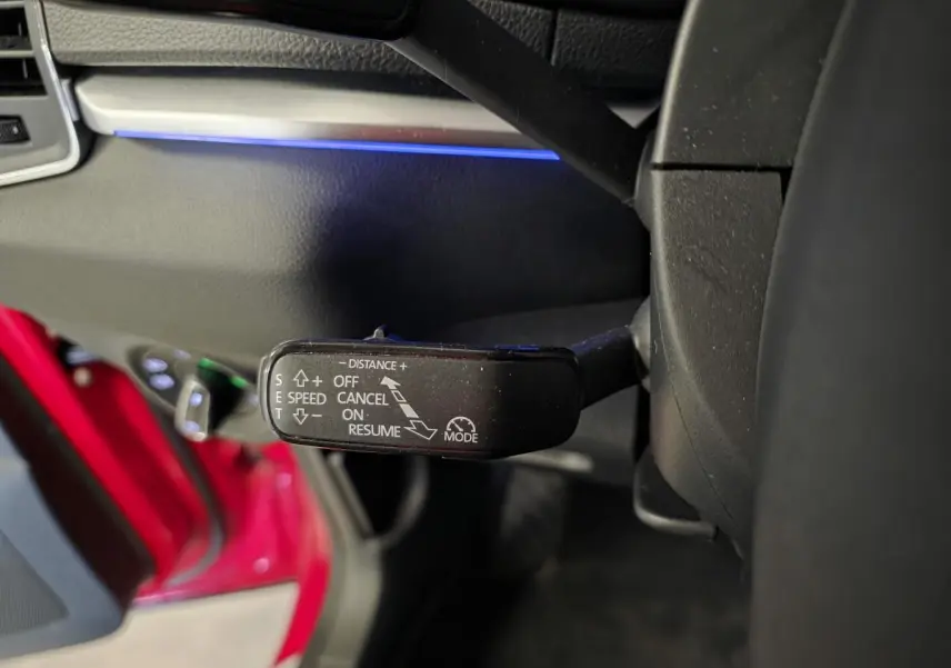 Le levier de commande du régulateur de vitesse dans l'habitacle côté gauche d'une Skoda Karoq rouge.