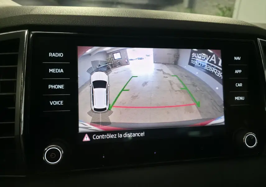 Affichage caméra de recul avec vue 360° du Skoda Karoq rouge, guidage de trajectoire et alertes de distance.